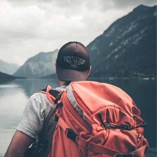 Hiker with backpack looking at a mountain in the diistance